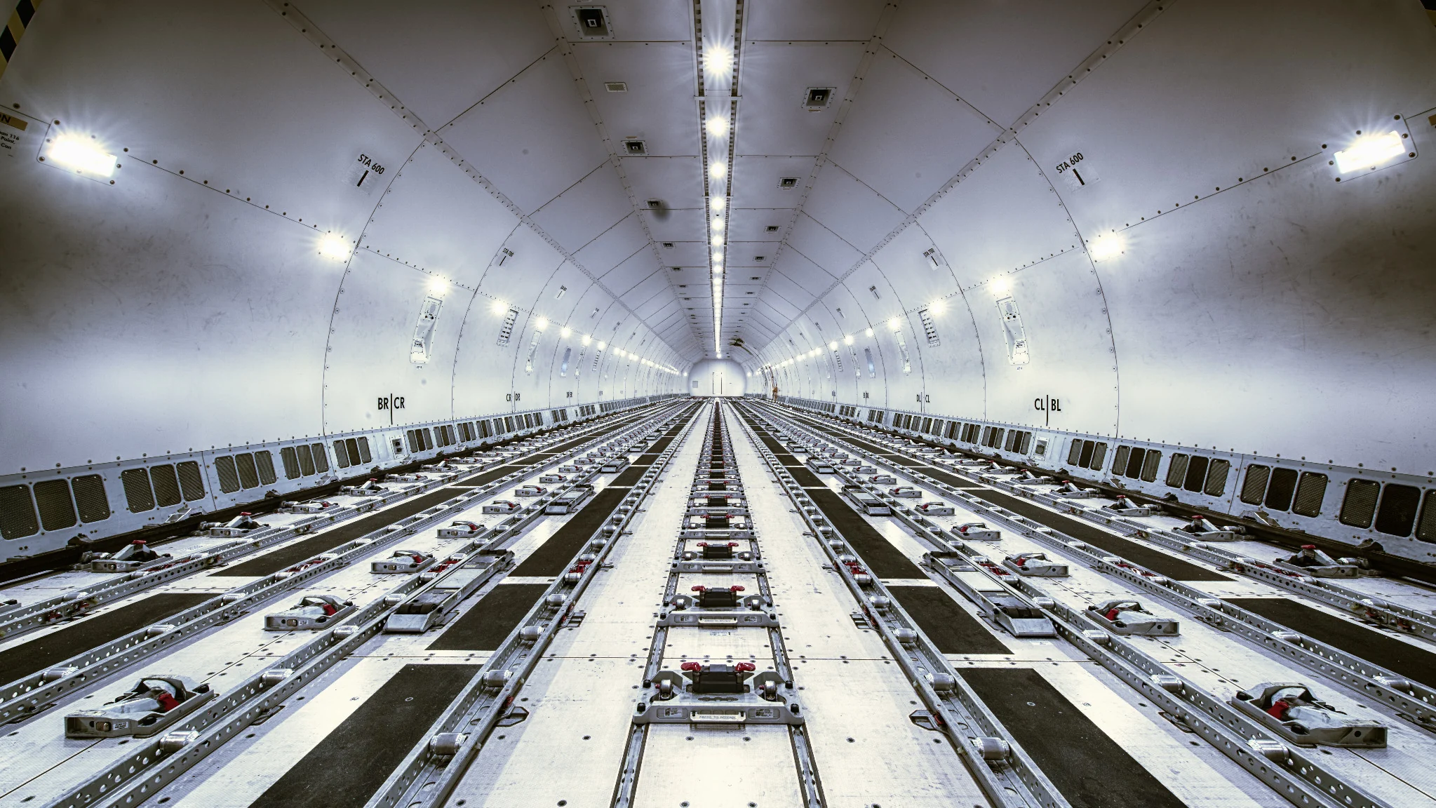 Empty main deck of a widebody freighter aircraft showing cargo rails and restraint positions